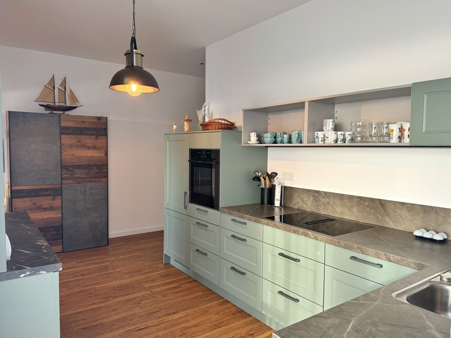 A modern kitchen with a built-in oven, a sink, and a wooden floor.