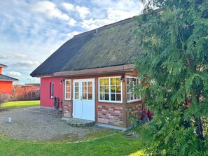 A small, single-story house with a thatched roof, a red brick exterior, and a white door. - Ferienhaus am Lebbiner Bodden (Neuenkirchen)