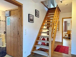 A wooden staircase with a handrail, a door with a sign, and a red rug on the floor.