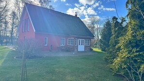 Une maison rouge avec un toit en pente, une porte d’entrée et un petit porche.