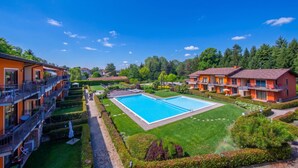 Ein Hotel mit Schwimmbad, mehreren Balkonen und einem gepflegten Garten.