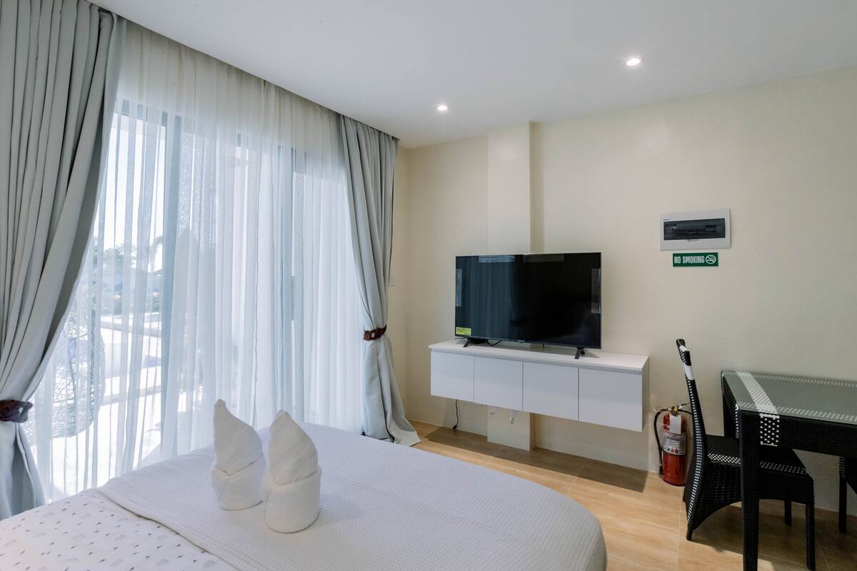 A hotel room with a bed, a TV, a small table, and a chair.