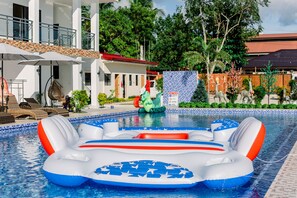 Ein Schwimmbecken mit aufblasbaren Spielsachen, Liegestühlen und einer überdachten Sitzgelegenheit.