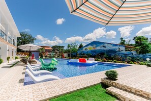 Ein Swimmingpool mit Liegestühlen, einem kleinen Schlauchboot und einem Wandgemälde.