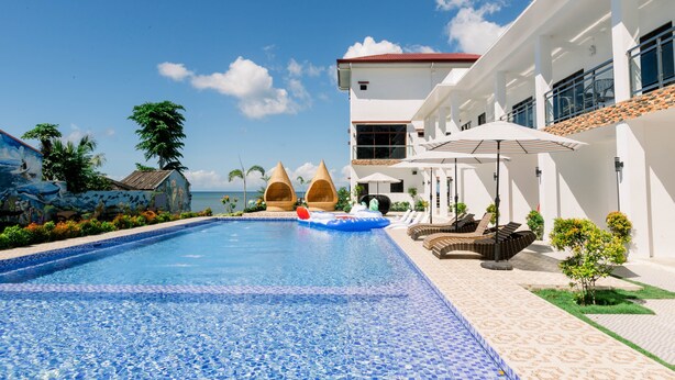 A swimming pool with a tiled edge, lounge chairs, and umbrellas. - Sonrisa Resort de Playa by Hiverooms (San Remigio)