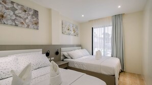 A hotel room with two beds, a large window with curtains, and artwork on the walls. - Sonrisa Resort de Playa by Hiverooms (San Remigio)