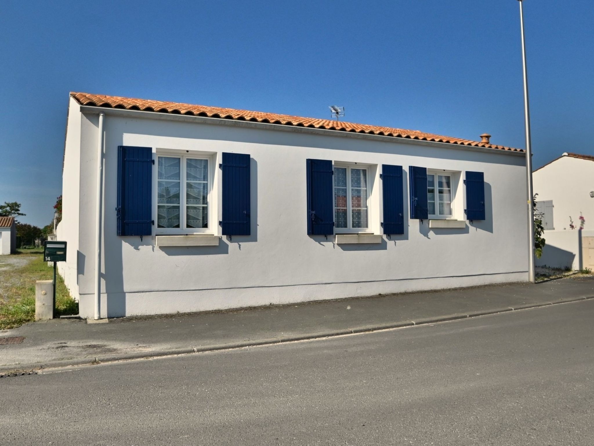 Un bâtiment d’un seul étage, à la façade blanche et au toit recouvert de tuiles.
