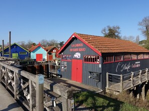 A row of colorful wooden buildings with a red door and signage indicating 'La Cabane du Sans Souci'. - La Parie 2 by Interhome (Ile d'Oléron)