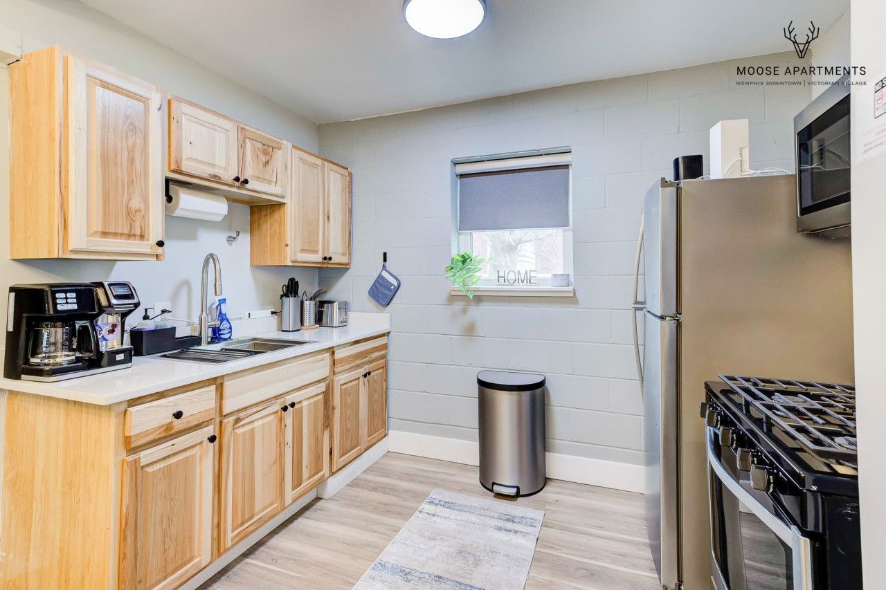 A modern kitchen with wooden cabinets, a stainless steel refrigerator, and a gas stove.