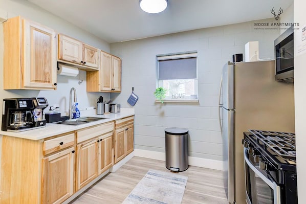 Una cocina moderna con armarios de madera, un refrigerador de acero inoxidable y una estufa a gas.