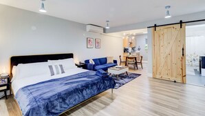 Un dormitorio moderno con una cama grande, un sofá azul, una mesita pequeña y una puerta corredera de madera.
