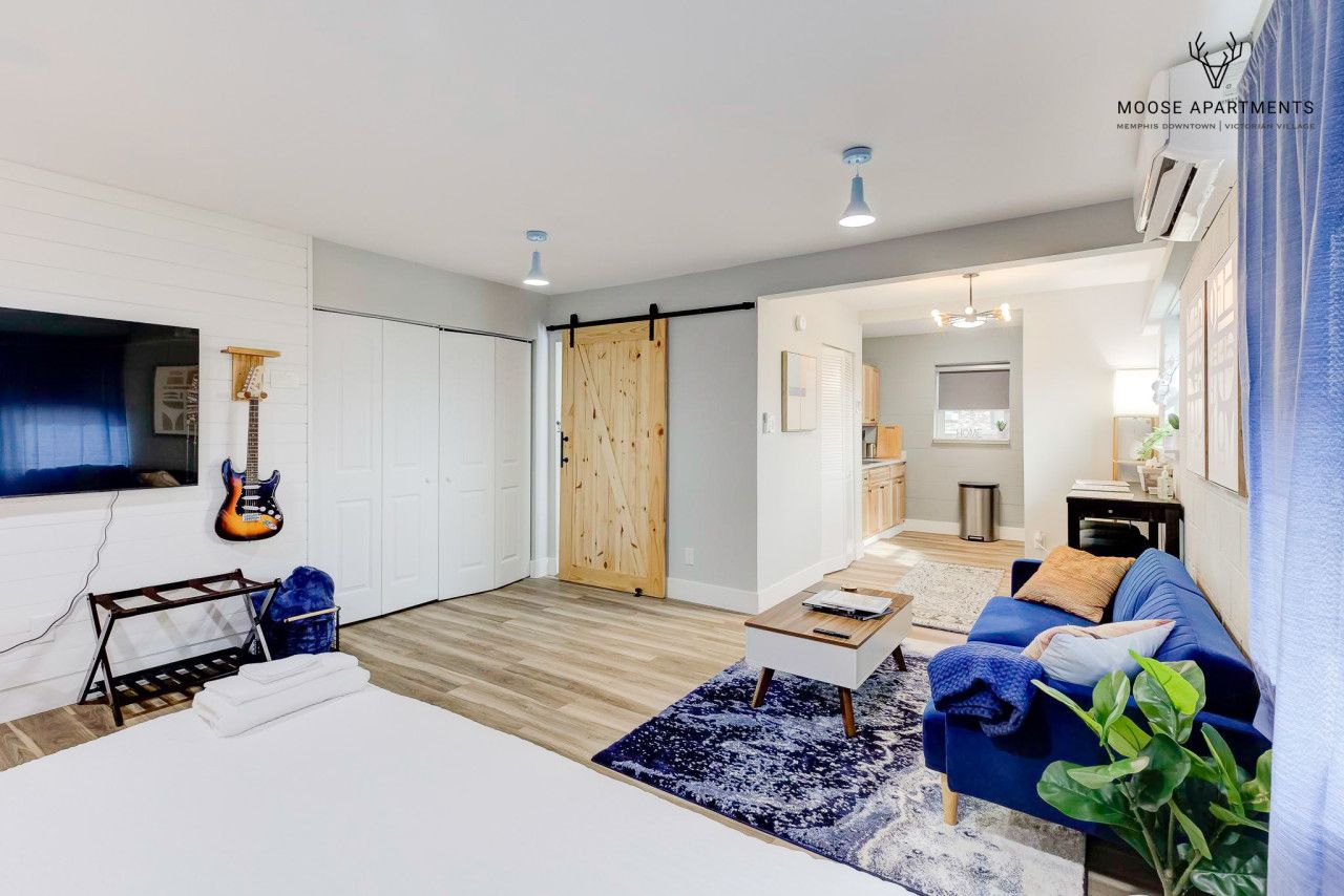 Un salón moderno con un sofá azul, una mesa de centro y una guitarra en la pared.