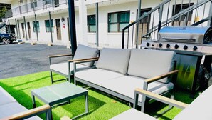 An outdoor seating area with a sofa, two tables, and a grill. - Modern Luxe Loft with King Bed, Free Parking & Wi-Fi (Memphis)