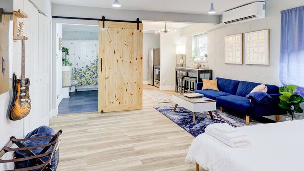 A modern living room with a blue sofa, wooden floor, and a sliding door. - Modern Luxe Loft with King Bed, Free Parking & Wi-Fi (Memphis)