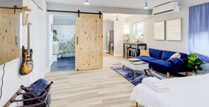 A modern living room with a blue sofa, a wooden sliding door, and a guitar on the wall.
