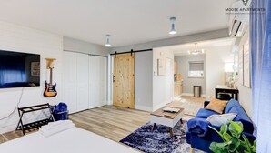 A modern living room with a blue sofa, a coffee table, and a guitar on the wall. - Modern Luxe Loft with King Bed, Free Parking & Wi-Fi (Memphis)
