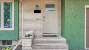 A house with a beige door, a mailbox, and a small planter with white flowers.