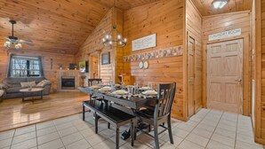 A wooden interior with a dining table set for four, a sofa, and a fireplace. - Epic Views • One Level • Hot Tub • Huge Fenced Yard • Pet Friendly • Easy Roads (Sevierville)