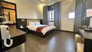 Una habitación de hotel con cama, mesita de noche y escritorio con teléfono.