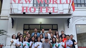 Un grupo de personas de pie frente a la entrada del Hotel New World.