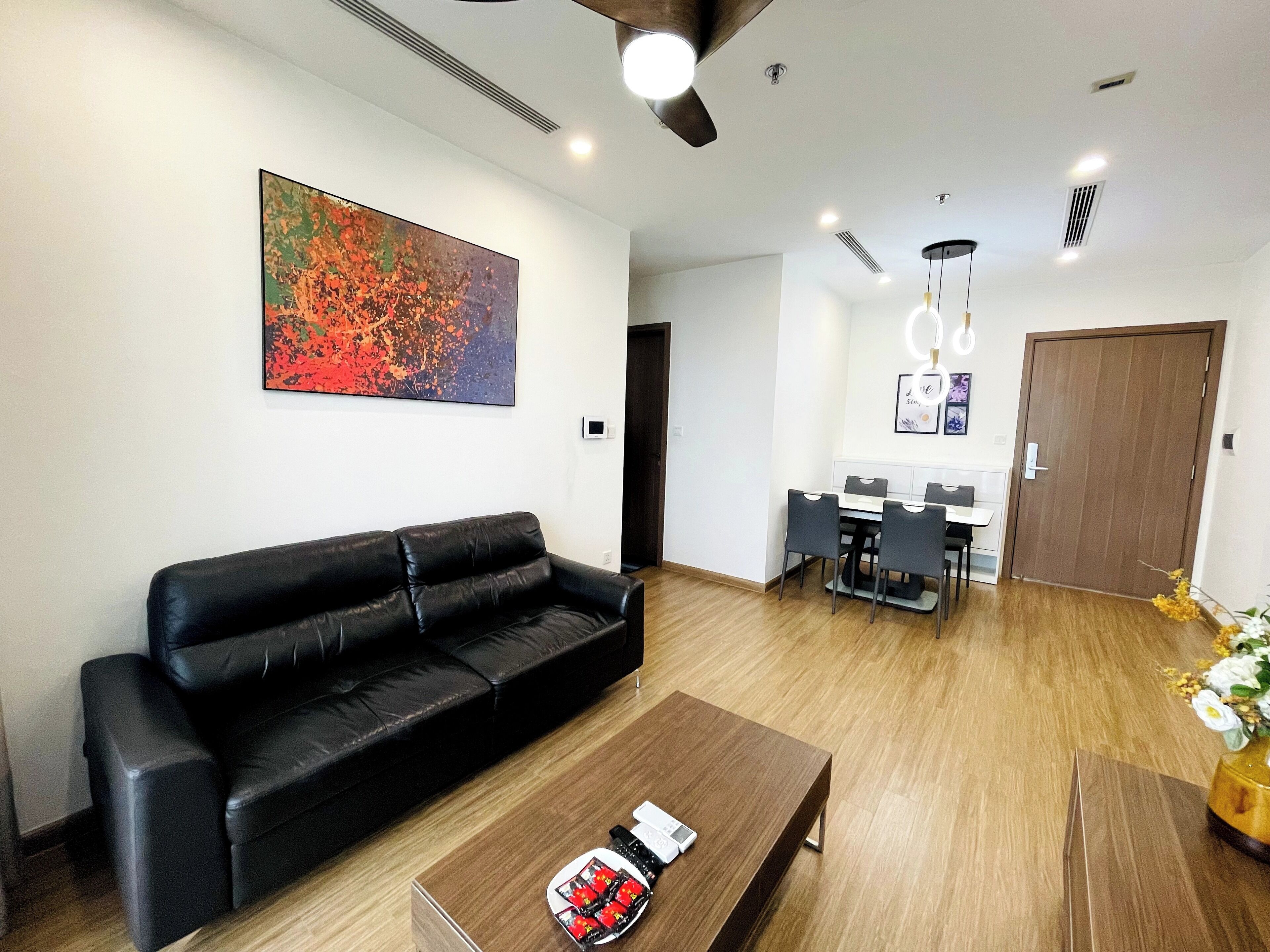 Ein modernes Wohnzimmer mit einer schwarzen Ledersofa, einem Holztisch und einem Essbereich mit weißem Tisch und schwarzen Stühlen.