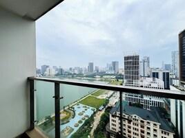 Vista panorámica de la ciudad desde un balcón, con un río y un parque en primer plano y edificios modernos al fondo.