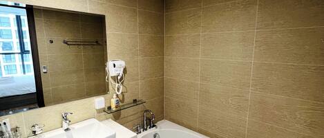 A modern bathroom with a large bathtub, two sinks, and a mirror above the sinks.
