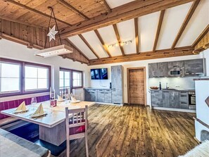 A spacious kitchen with modern appliances, a dining area with a wooden table and chairs, and a large window providing natural light.