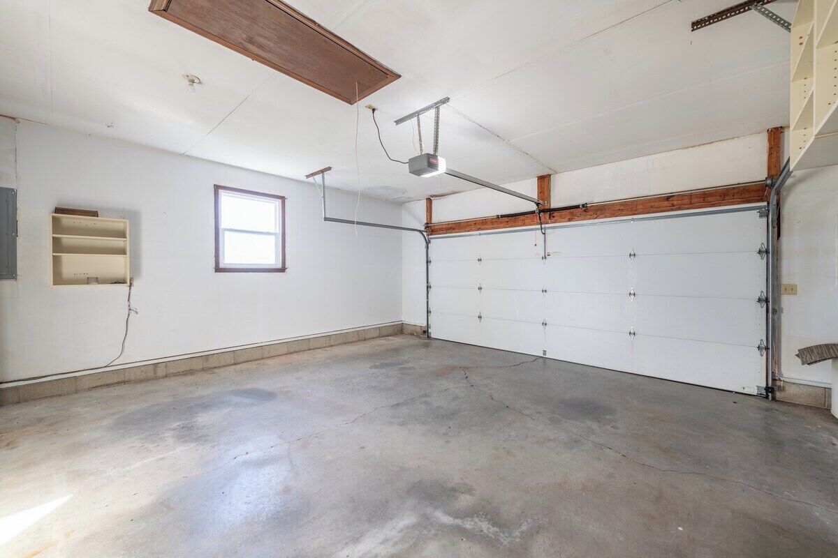 A garage with a concrete floor, a white garage door, and a window.