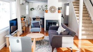 Ein geräumiges Wohnzimmer mit Kamin, Holzboden und einer Wendeltreppe.