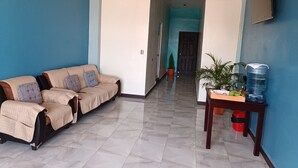 A modern living room with a beige sofa, a small table with a plant, and a water dispenser. - Casa chikuwa  (San Juan La Laguna)