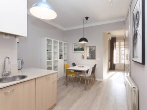 A modern kitchen with a built-in oven, a white cabinet, and a dining area with a table and chairs.