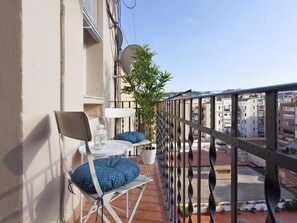 A balcony with a chair, a small table, and a potted plant.