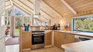 Una cocina moderna con armarios de madera, electrodomésticos de acero inoxidable y un amplio ventanal con vistas al exterior.