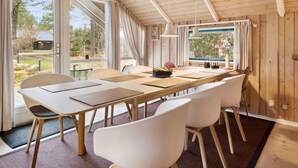 Un comedor con una mesa larga, sillas blancas y vistas al exterior.