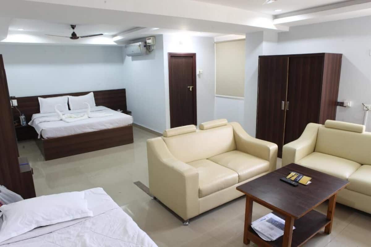 Ein Hotelzimmer mit einem Bett, zwei Sofas, einem Couchtisch, einem Kleiderschrank und einer Tür.