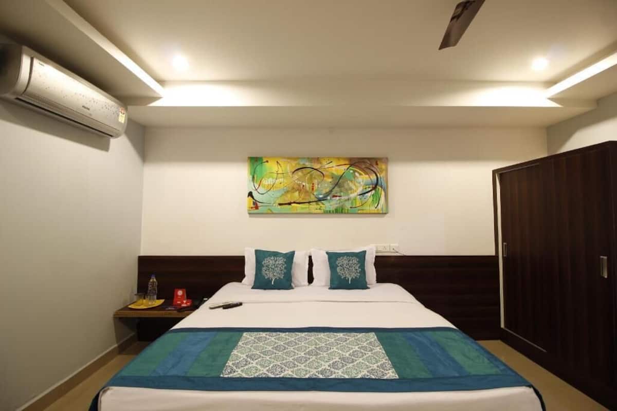 Ein Hotelzimmer mit Bett, Nachttisch, Klimaanlage, Holzschrank und einem Bild an der Wand.