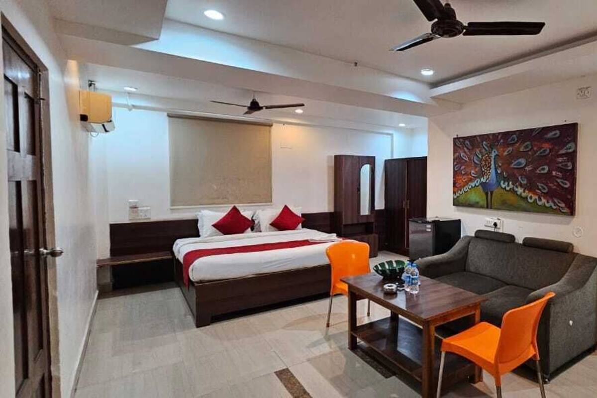 Ein modernes Hotelzimmer mit Bett, Sofa, Tisch und Fernseher.