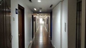 Een lange, smalle gang met deuren aan beide kanten, die naar afzonderlijke kamers leidt.