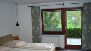 A bedroom with two beds, a window with a view of greenery, a radiator, and a hanging light fixture. - Apartment 'Ferienwohnungen Memminger' with Private Terrace and Wi-Fi (Aicha vorm Wald)
