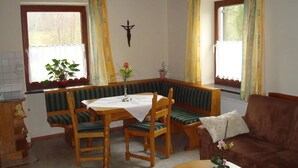 A cozy room with a wooden table, two chairs, a bench, a sofa, and a radiator. - Apartment 'Ferienwohnungen Memminger' with Private Terrace and Wi-Fi (Aicha vorm Wald)