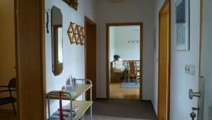 Un pasillo con un escritorio, un espejo y una puerta que da a una habitación.
