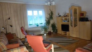 Una sala de estar con sofá, sillón, televisor y aparador.