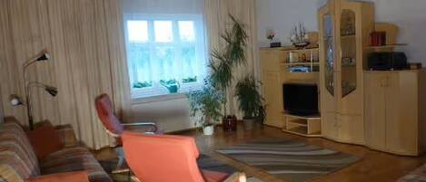 A living room with a sofa, a chair, a television, and a cabinet.