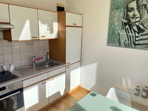 Une cuisine moderne avec des meubles blancs, un évier en acier inoxydable, un four encastré et un plan de travail en bois.