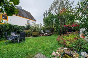 Un jardin avec une pelouse, une table et des chaises, un banc et une statue.