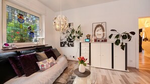 Un salon moderne avec une table basse en verre, un canapé en cuir noir, un meuble blanc et un vitrail.