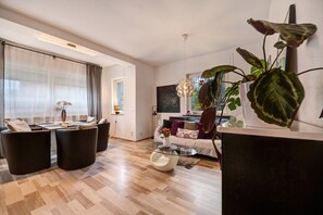 Un salon moderne avec une table basse en verre, un canapé et un coin repas avec des chaises.
