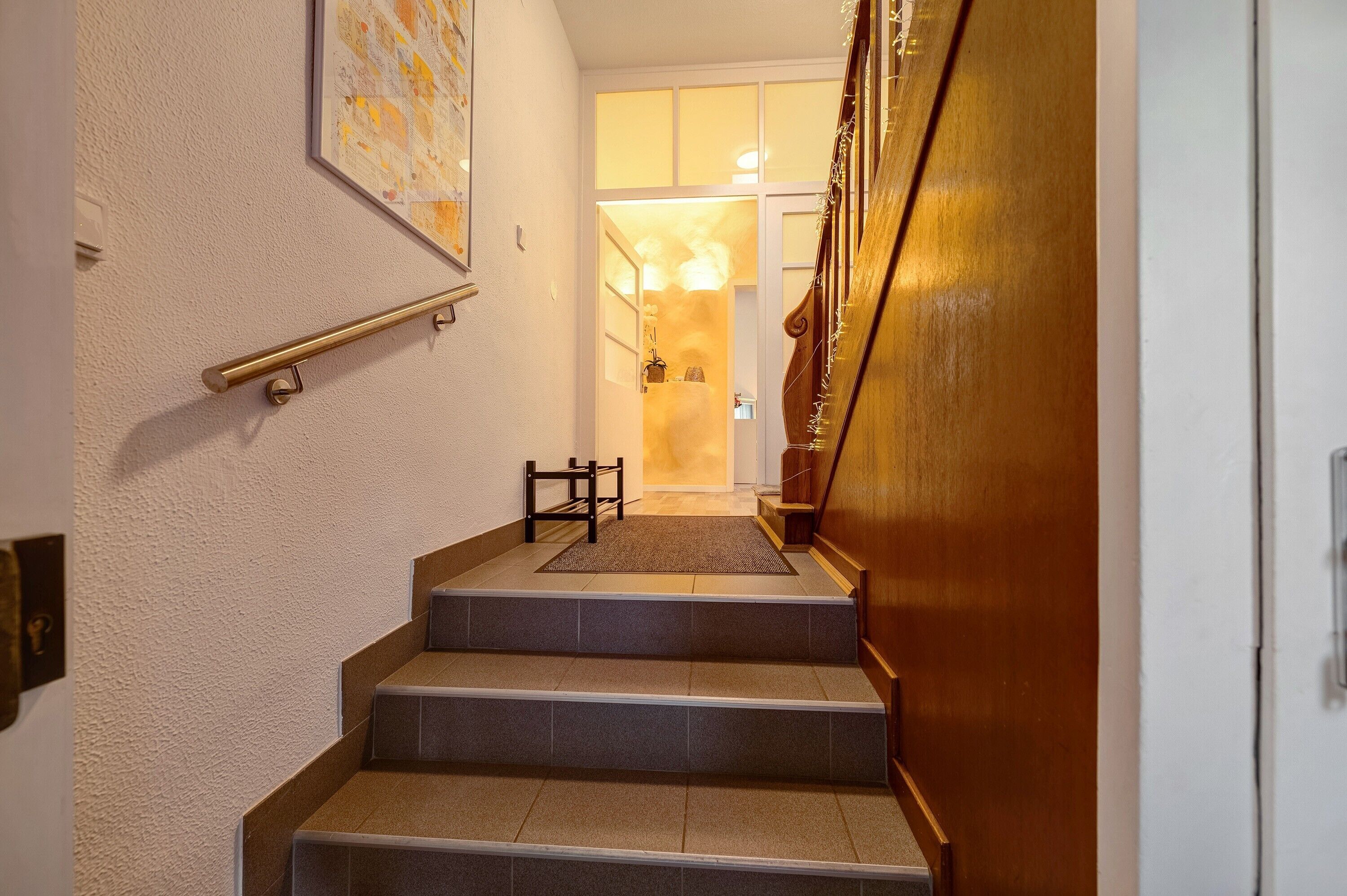Una escalera con barandilla, una puerta al final y un accesorio de iluminación en la parte superior.