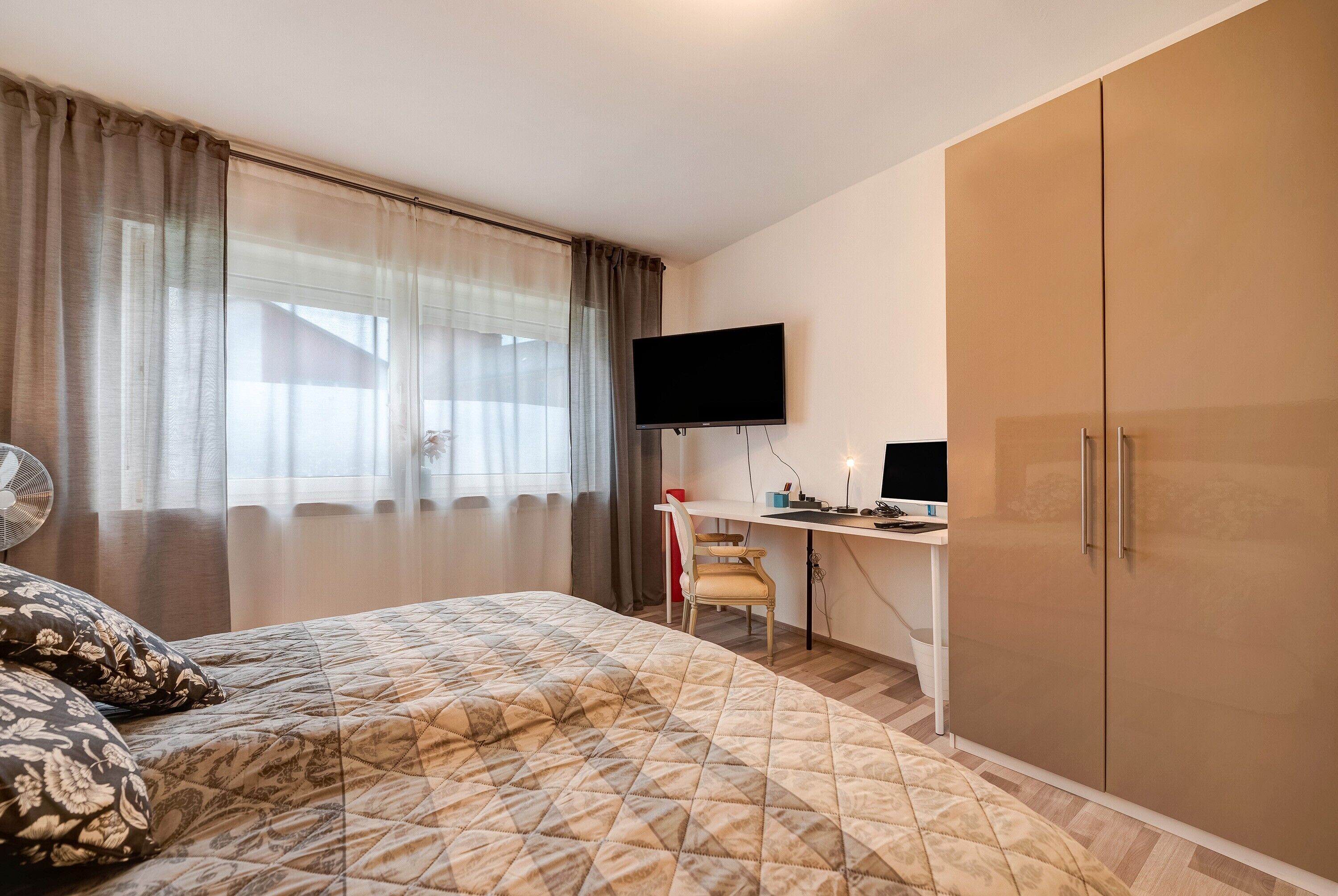 Ein Schlafzimmer mit einem Bett, einem Schreibtisch, einem Fernseher und einem Kleiderschrank.